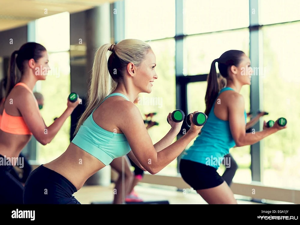 Fitness Sport and healthy Lifestyle Concept - smiling young woman with Dumbbells exercising at Home